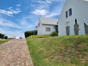 una casa blanca en una colina con una entrada de ladrillo en The Dune Hideaway, en Port Alfred