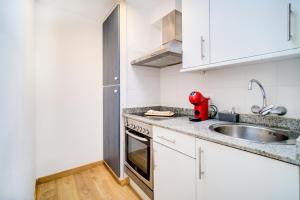 - une cuisine blanche avec un évier et un appareil rouge dans l'établissement Surmar - Apartamento con piscina en Cap d'Artrutx, à Cala'n Bosch