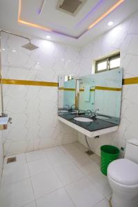 een badkamer met een wastafel, een spiegel en een toilet bij Hotel Orange One in Lahore