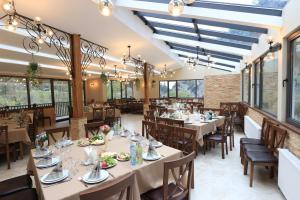 - une salle à manger avec des tables, des chaises et des fenêtres dans l'établissement Dzeruli, à Tkibulges