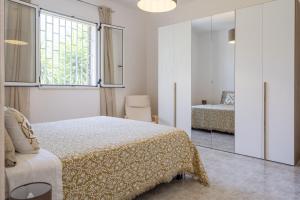 Habitación blanca con cama y espejo en Bouganvillea Villa in Ostuni, en Ostuni