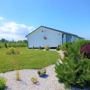 a white barn with plants in a yard at Słoneczne domki nad morzem in Darłowo