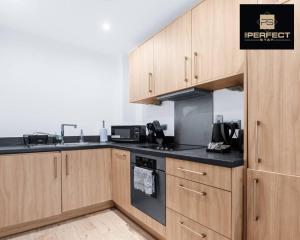 a kitchen with wooden cabinets and a stove top oven at Mercury Suite CITY CENTRE Netflix Dedicated Workspace By Your Perfect Stay Short Lets Birmingham in Birmingham