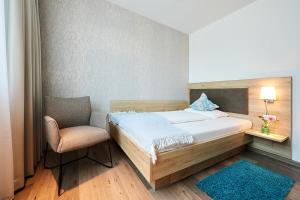 a small bedroom with a bed and a chair at Hotel Sarah in Heinsberg