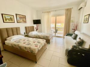 Habitación de hotel con 2 camas y sofá en Sea Apartments Himare, en Himare