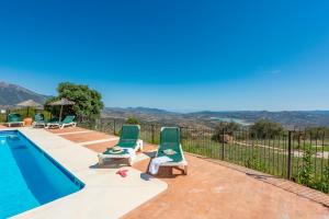 a villa with a swimming pool and two lawn chairs at Cantueso Holiday Park in Periana