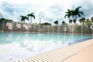 a swimming pool with a fence and palm trees at Candlewood Suites Miami Intl Airport - 36th St, an IHG Hotel in Miami