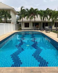 einem großen blauen Pool mit Palmen und einem Haus in der Unterkunft Loma-asunto Hua Hin Soi 94 Baan Finland apartment 28 in Hua Hin