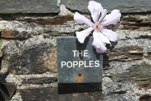 a sign on a stone wall with a flower on it at Charming 2-Bed Cottage in Modbury in Modbury