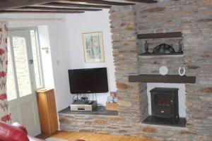 a living room with a stone fireplace with a television at Charming 2-Bed Cottage in Modbury in Modbury