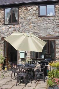 a table with an umbrella in front of a building at Charming 2-Bed Cottage in Modbury in Modbury