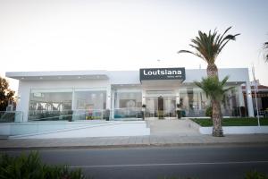 a building with a palm tree in front of it at Loutsiana Deluxe Apts in Ayia Napa
