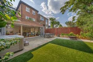 a backyard with a lawn and a house at Stunning 3B2Ba Huge entertaining space and hottub! in Raynes Park