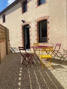 una mesa amarilla y sillas frente a un edificio en Gîte O Petit Bouchon à 10 min du Puy du Fou en Sevremont