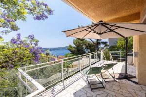 a patio with two chairs and an umbrella at VILLA CRUG HYWEL - VILLEFRANCHE-SUR-MER in Villefranche-sur-Mer