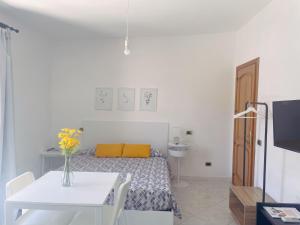 a white room with a bed and a table with a yellow pillow at Stars Home in Tropea