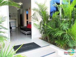 una sala de estar con un sofá negro y algunas plantas en Hostal Playa Imperial Manta, en Manta