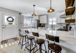a kitchen with white cabinets and bar stools at YellowDoorBeachHouse close to Moonlight Beach and LEGO Land in Encinitas