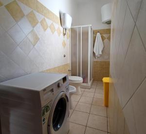 a bathroom with a washing machine and a toilet at Zia Peppina in Tertenìa
