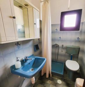 a bathroom with a blue sink and a toilet at Lofos ClaudiAgapi Guesthouse Seaview in Agios Stefanos