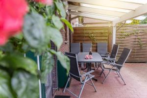 un patio con mesa, sillas y una valla en Ferienwohnung 50027, en Wangerland