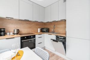 a kitchen with white cabinets and a table and chairs at Green View Apartment with Balcony Winogrady by Noclegi Renters in Poznań
