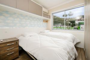 Duas camas num pequeno quarto com uma janela. em SDF - Apartamentos lindos em Floripa-SC em Florianópolis