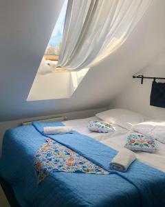 a bed with blue sheets and pillows and a window at Folwark Nadmorska Ostoja in Mechelinki