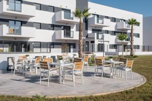 un patio con mesas y sillas frente a un edificio en Residencial Celere Playa Niza en Almayate Bajo