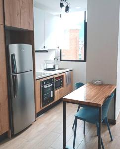 a kitchen with a table and a stainless steel refrigerator at Lindo e iluminado apartaestudio en La Carolina in Quito