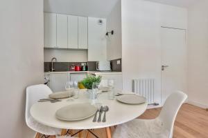 una mesa blanca con sillas blancas y una cocina blanca en Studio - Appartement Quartier Montparnasse 2 en París