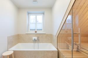 una bañera en un baño con ventana en Biikehuus West, en Niebüll