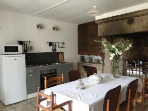 a kitchen with a white table and a white refrigerator at Maison du Bûcheron in Melay