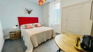 1 dormitorio con 1 cama con cabecero rojo y mesa en Locanda alla Grotta, en Crone
