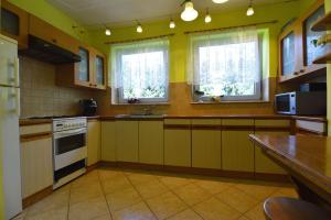 uma cozinha com paredes amarelas, balcões e janelas em Dom wśród Modrzewi em Uście Gorlickie