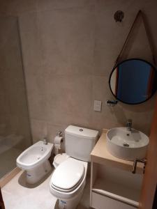 uma casa de banho com um WC, um lavatório e um espelho. em Departamento en Corrientes em Corrientes