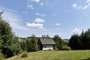 a small house on a hill in a field at Dom wśród Modrzewi in Uście Gorlickie