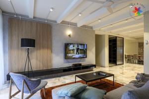 KL Townhouse Villa by LilyandLoft في كوالالمبور: غرفة معيشة مع أريكة وتلفزيون على الحائط