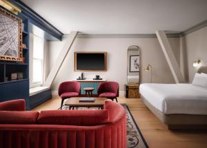a hotel room with a bed and red chairs at The Union Station Nashville Yards, Autograph Collection in Nashville