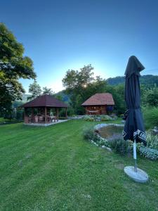 an umbrella in the middle of a yard with a gazebo at Šum Rzava in Arilje