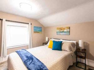 a bedroom with a bed with blue and yellow pillows at Wine Valley Bungalow in Ashtabula