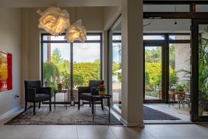 a living room with glass doors and chairs and a chandelier at Hotel i Restauracja Czarny Kos in Borkowo