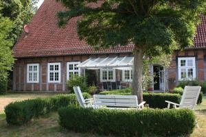 two white chairs and a tree in front of a house at Flett - Artlands Home - Landhaus für Familien und Gruppen in Badbergen