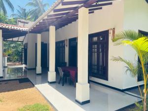 une maison avec une terrasse couverte munie d'une table. dans l'établissement Harini Villa, à Sigirîya