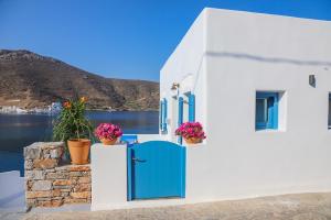 a white house with a blue door and flowers at Gialos Studios in Katapola