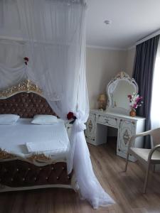 a white bedroom with a bed with a canopy at Hotel Дар-Ай in Kostanay