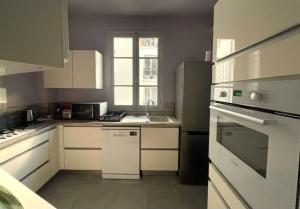 eine kleine Küche mit weißen Schränken und einem Fenster in der Unterkunft GUSTAVE - Charming Eiffel Tower Appartement - in Paris