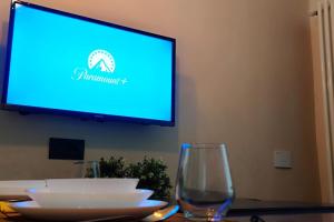 a television with a blue screen and two glasses on a table at Casa Relax - 500 mt. dal Centro in Turin