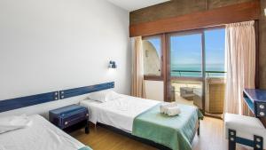a bedroom with two beds and a balcony with the ocean at 1BDR Apartment W/Beach View by LovelyStay in Monte Gordo