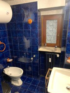 La salle de bains est pourvue de carrelage bleu, de toilettes et d'un lavabo. dans l'établissement Appartamento BREUIL CERVINIA, à Breuil-Cervinia